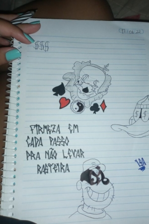 Mão segurando um caderno fácil com desenhos e texto em português dizendo "Firmeza em cada passo pra não levar rasteira. Para Colorir.