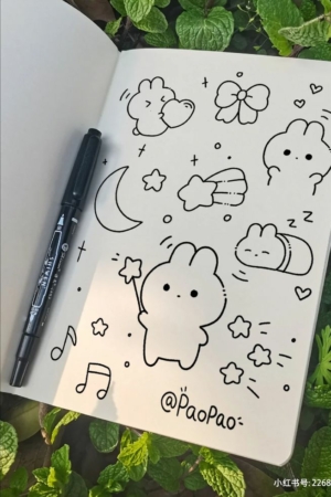 Um caderno com rabiscos de coelhos do Desenho fofo e uma caneta, cercado por plantas verdes. Para desenhar.