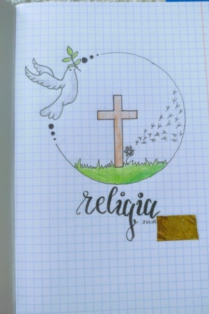 Uma página de caderno com um desenho de uma pomba, uma cruz, grama e dentes-de-leão, e a palavra "religião" escrita em cursiva enfeitam a capa do caderno.