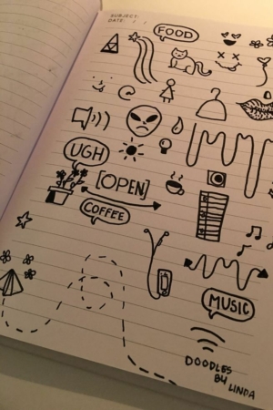 Página de caderno cheia de rabiscos, incluindo alienígenas, comida, temas musicais e várias formas aleatórias. O texto "DOODLES BY LINDA" adorna o topo do caderno, exibindo seu desenho caprichoso. Para desenhar.