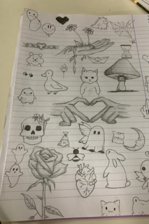 Uma página de caderno pautada repleta de vários desenhos a lápis, incluindo animais, flores, fantasmas e formas abstratas. Para desenhar.